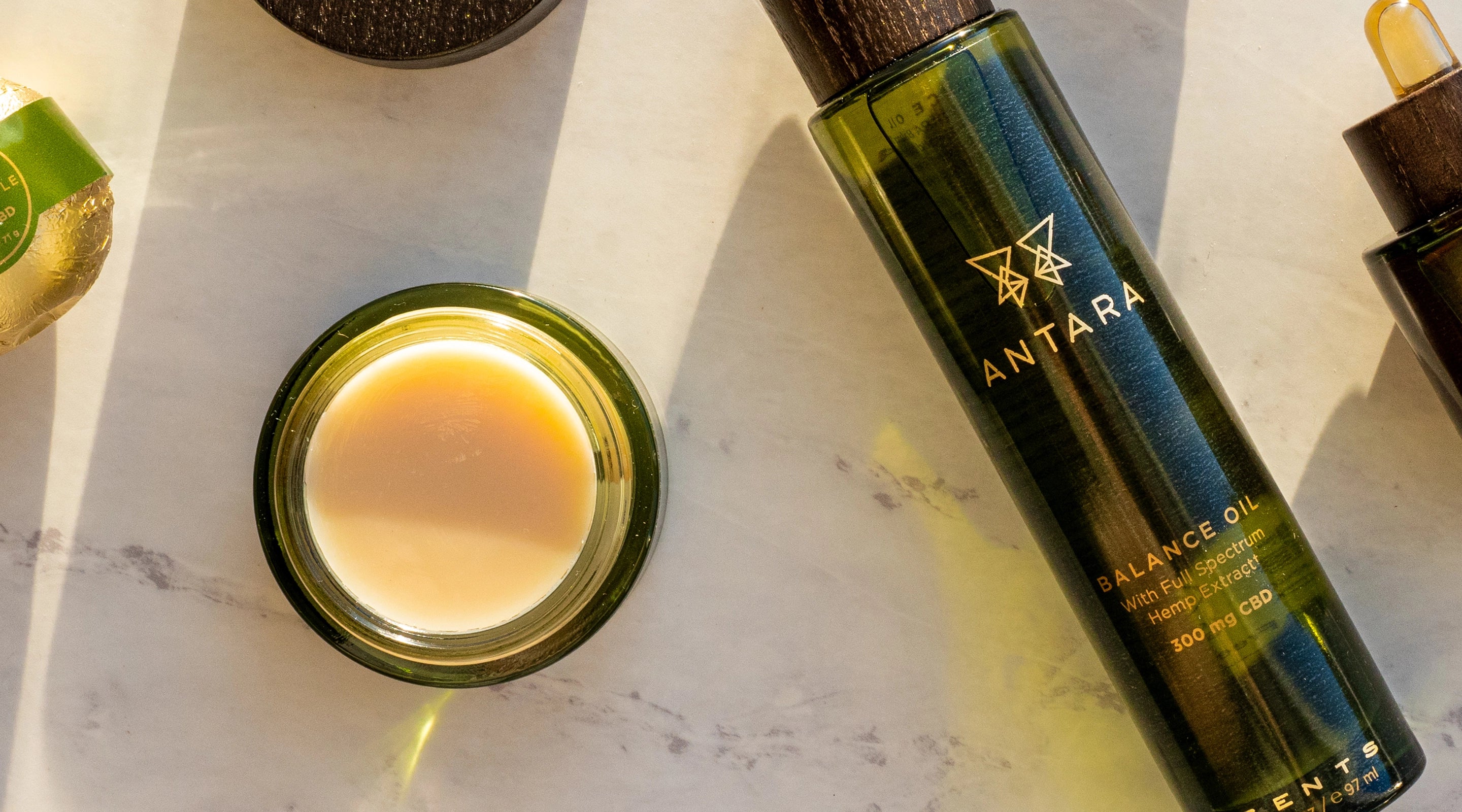 Antara skincare products including a bottle, jar, and dropper on a marble surface.