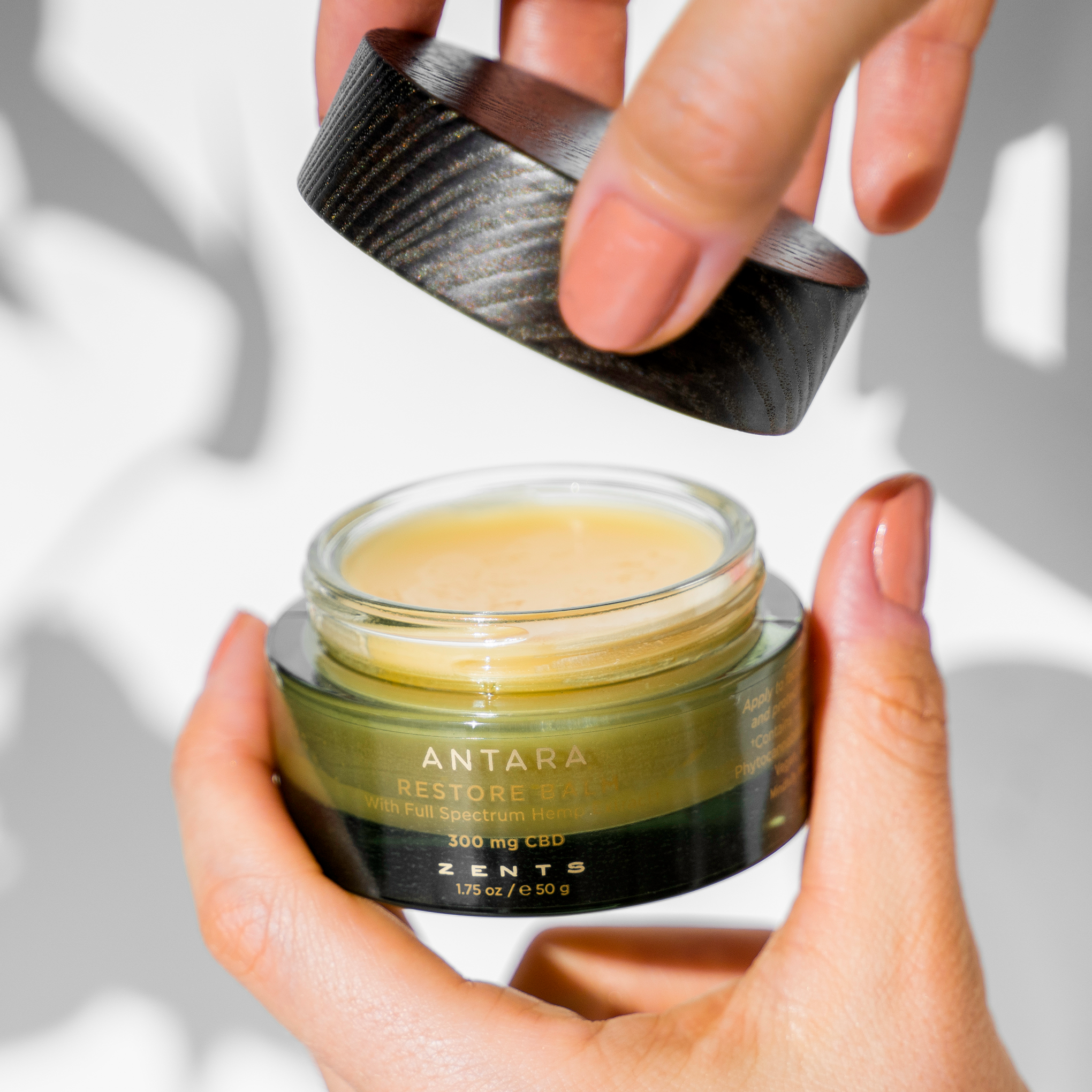 Woman taking wooden lid off restore balm 300 milligram jar