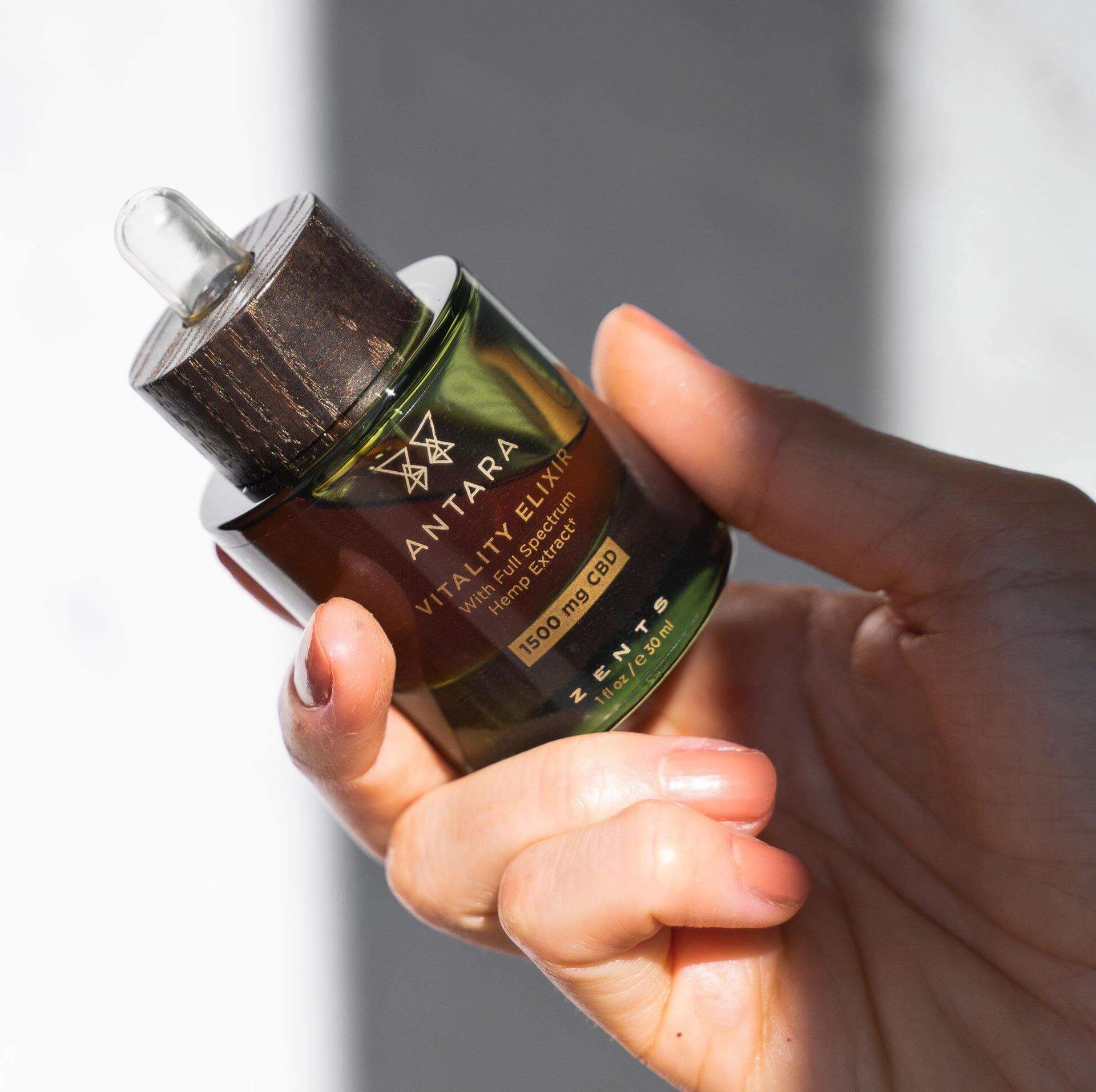 Bottle of vitality elixir 1500 mg CBD oil being held in hand.