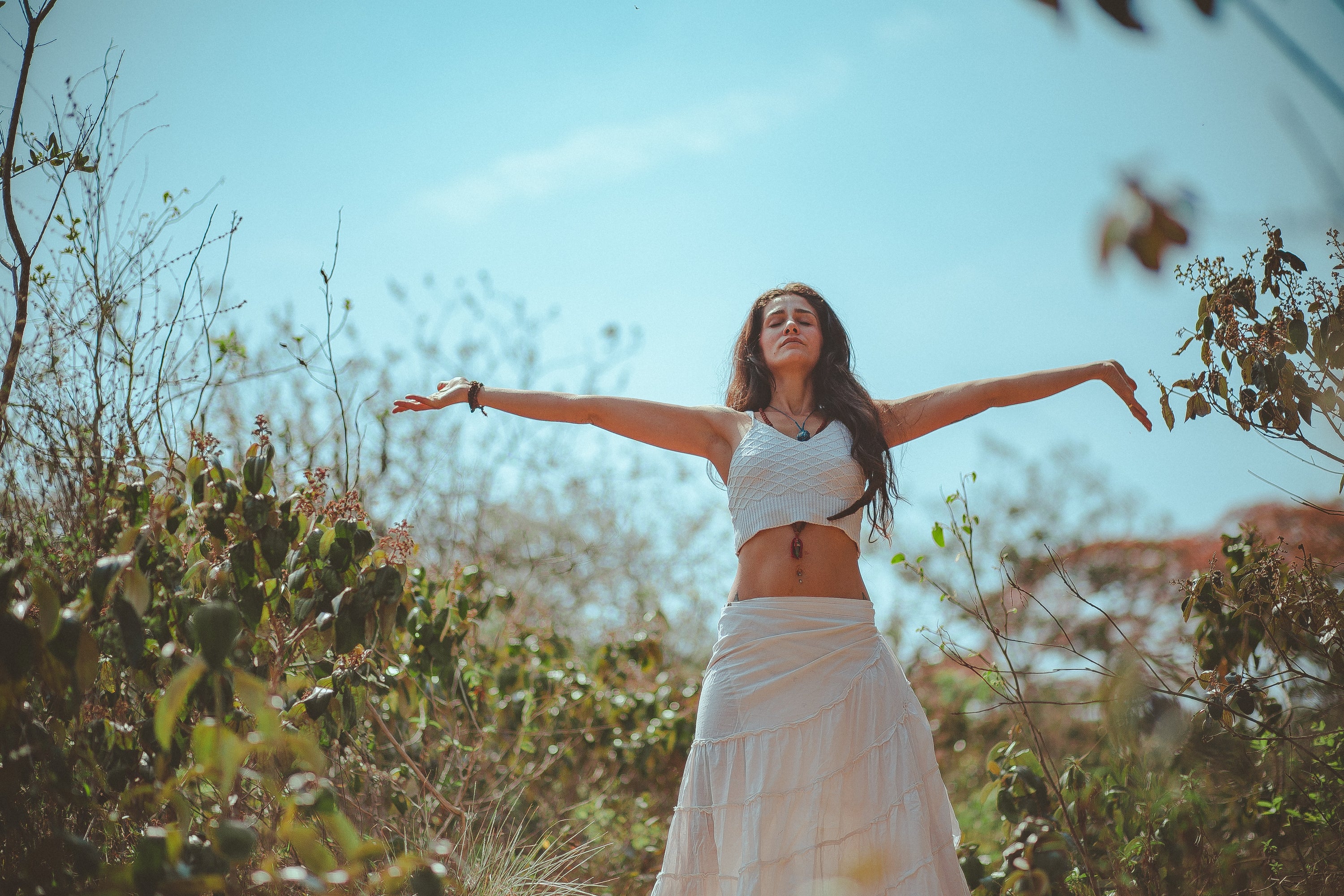 Woman spreading her arms and practicing wellness tips for summer 2023.